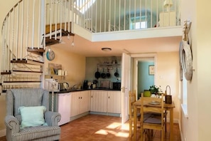 A kitchen with a dining area, a staircase, and a view of the sky.