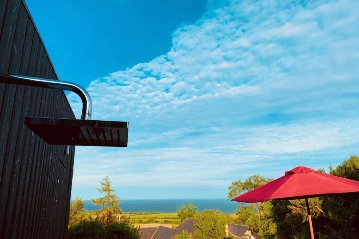A wooden building with a view of the ocean and a red umbrella.