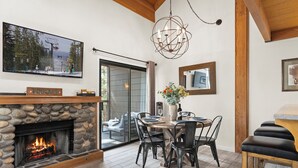 Un comedor acogedor con chimenea de piedra, techo de madera y un ventanal grande.
