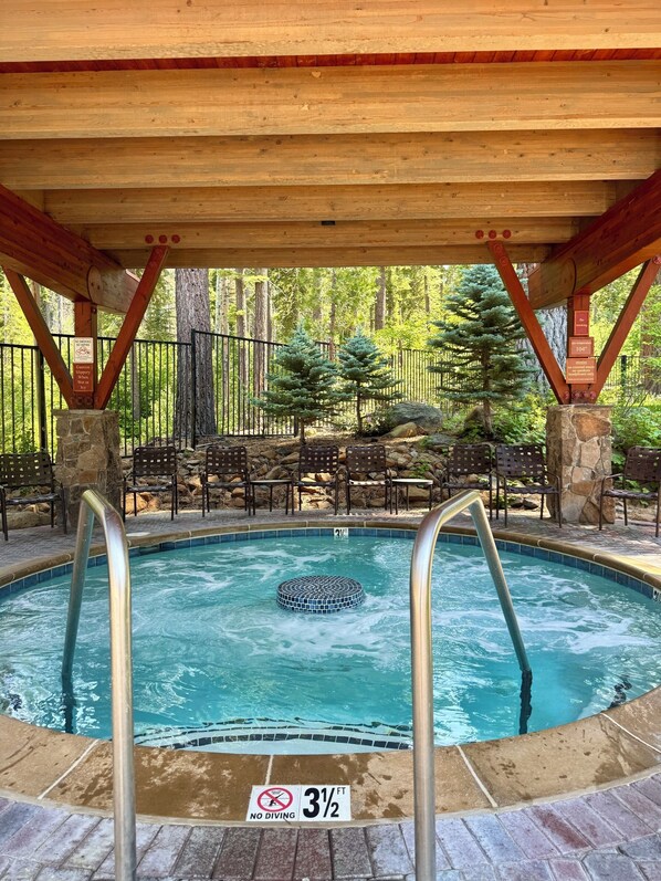 A pool with a no diving sign, a 3 1/2 ft depth marker, and a wooden deck with chairs and a stone wall.