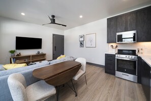 Une cuisine moderne avec des meubles de couleur sombre, un four à micro-ondes encastré et une cuisinière en acier inoxydable.