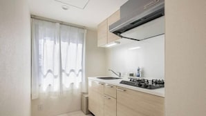 A modern kitchen with a gas stove, sink, and light wood cabinets. - Cantabile Meidaimae (Tokyo)