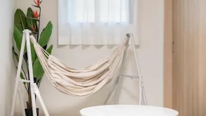 A room with a white round table, a beige hammock, and a potted plant with large leaves. - Cantabile Meidaimae (Tokyo)