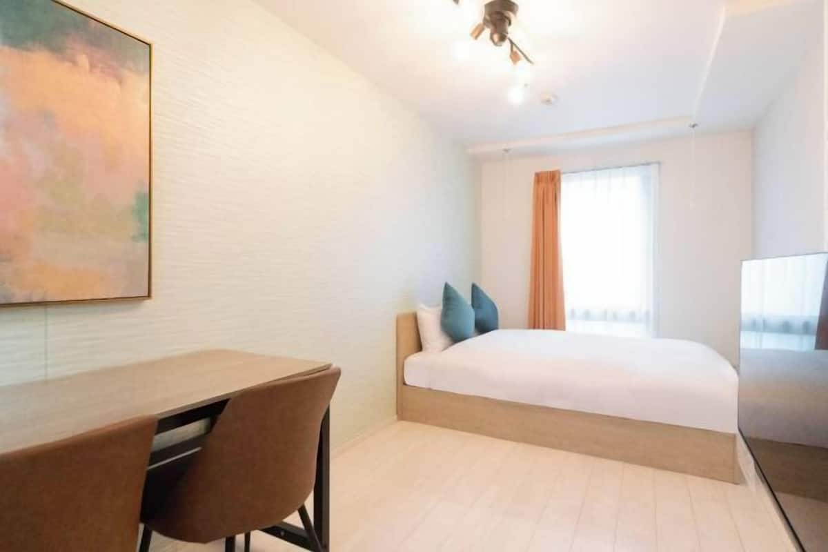 A hotel room with a bed, a desk, and a chair.