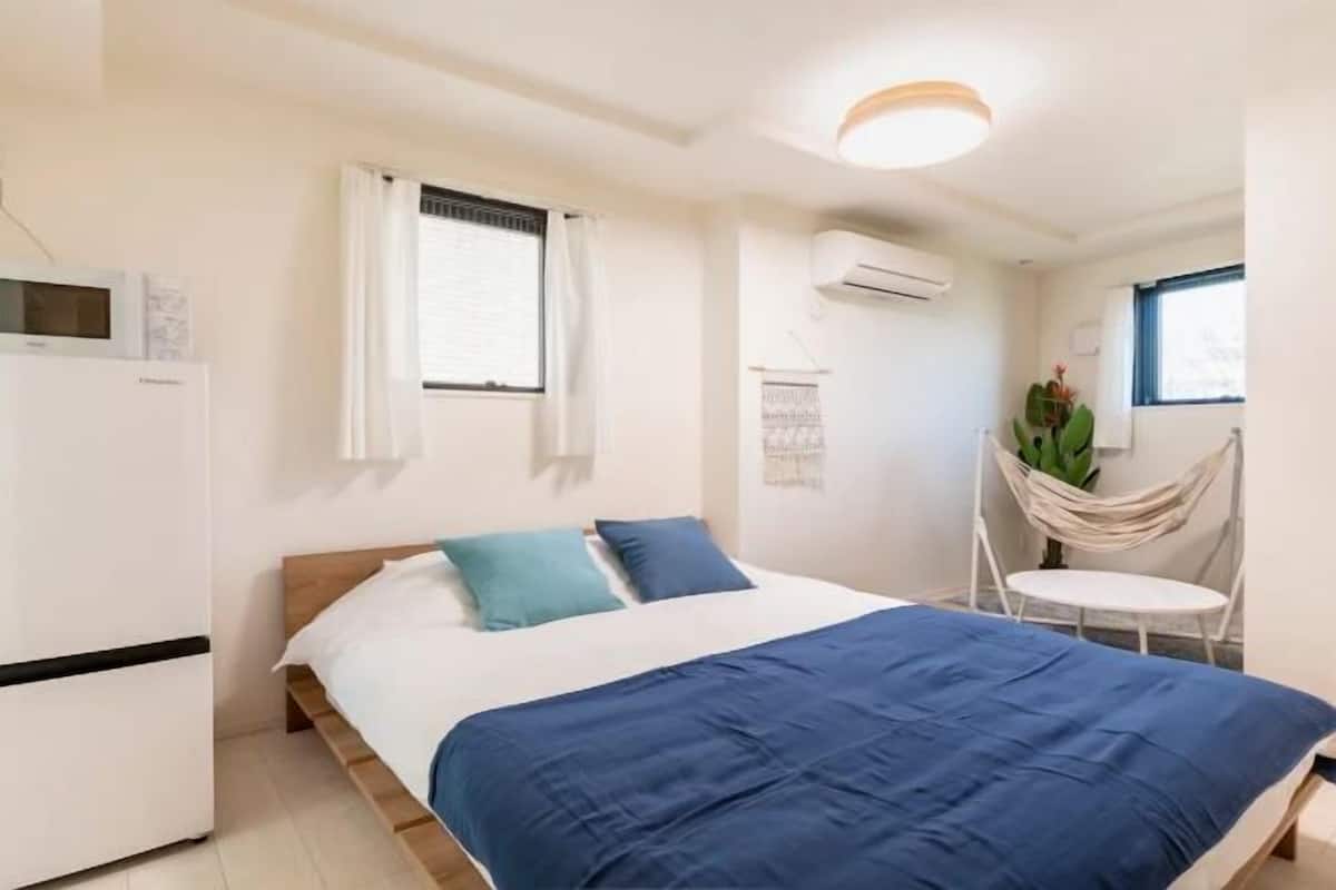 A bedroom with a bed, a small table, and a chair.