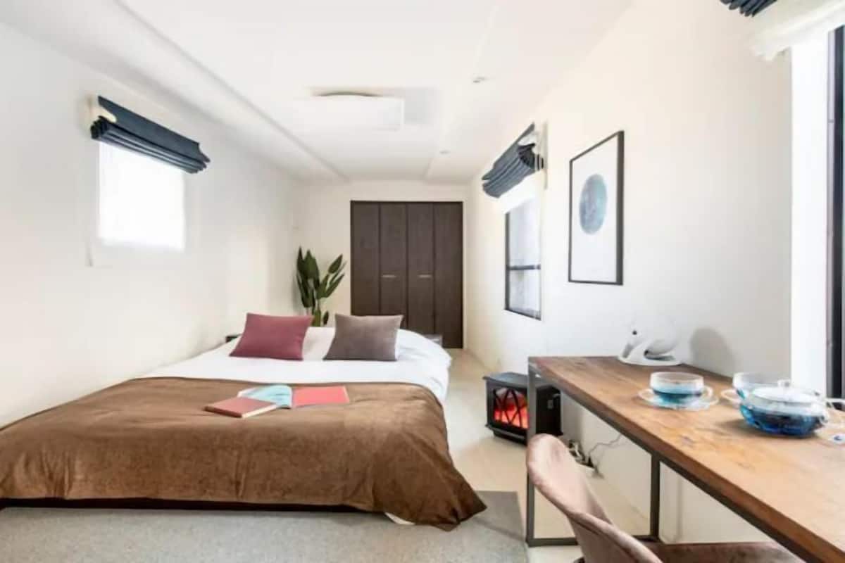 A modern hotel room with a bed, bedside table, and a small desk with a chair.
