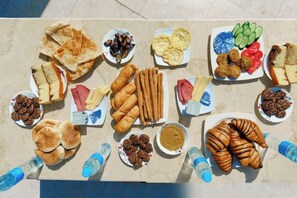 A variety of food items arranged on a table, including sandwiches, pastries, and dips.
