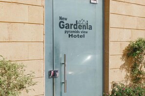 A building with a sign reading 'New Gardenia Pyramids View Hotel.'