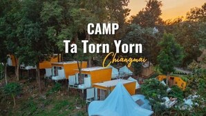 A camp with multiple elevated structures, some with attached platforms and others with open sides, surrounded by dense greenery. - CAMP Ta Torn Yorn (Mae On)