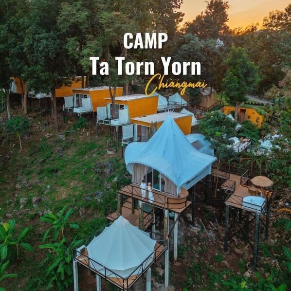 A camp with multiple elevated structures, some with attached platforms and others with open sides, surrounded by dense greenery. - CAMP Ta Torn Yorn (Mae On)