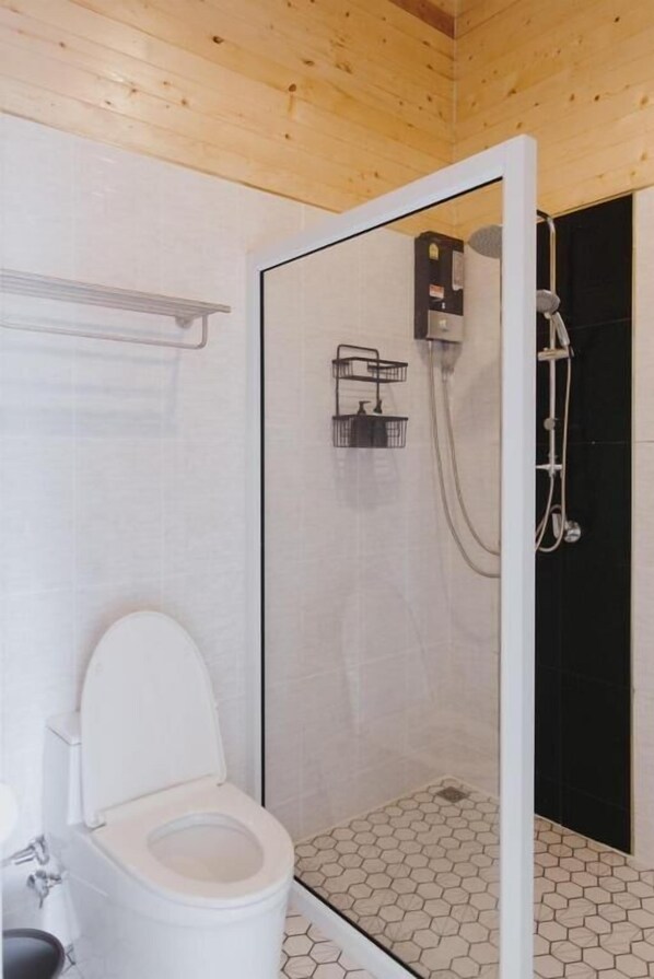 Une salle de bain comprenant des toilettes, un espace douche et un sol carrelé.
