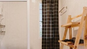 A bathroom with a hexagonal tile floor, a white toilet, a shower with a glass door, and a wooden shelf with towels. - CAMP Ta Torn Yorn (Mae On)