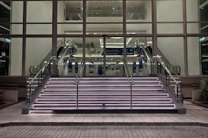 A set of stairs leading to an elevator in a modern building with large windows.