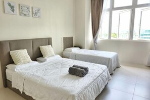 A hotel room with two beds, a large window, and artwork on the wall.