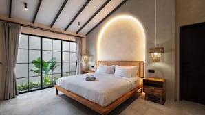A modern bedroom with a large window, a wooden bed, and a wall-mounted light fixture. - MDF Villa Canggu (Bali)