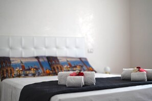 A neatly made bed with a black bedspread, a white headboard, and a pillow with a cityscape design. - Sybilvilla (Oriago)