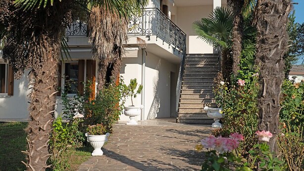 A building with a stone pathway leading to a balcony with a wrought iron railing.