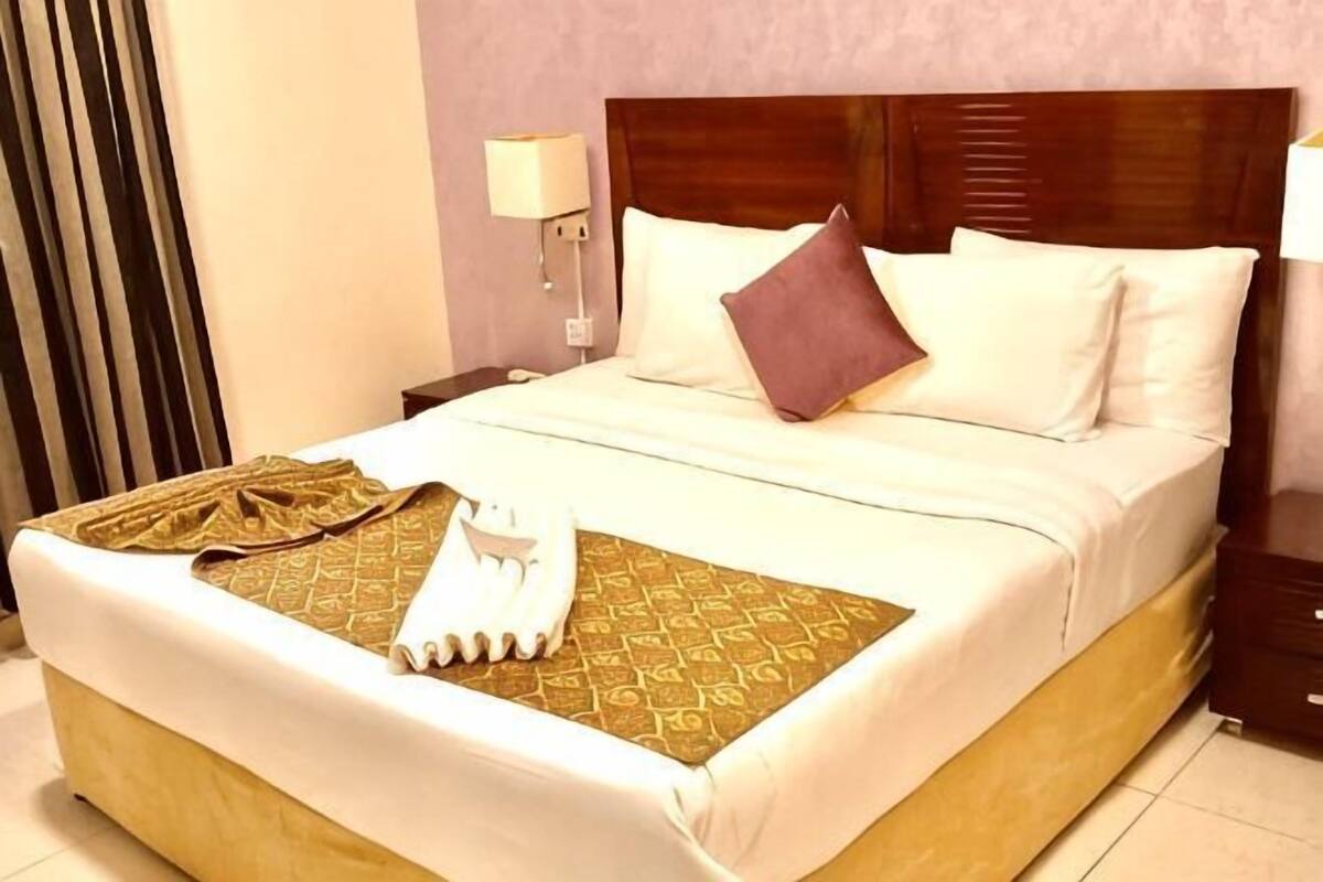 Cama bem arrumada com colcha estampada, travesseiros e toalha dobrada.