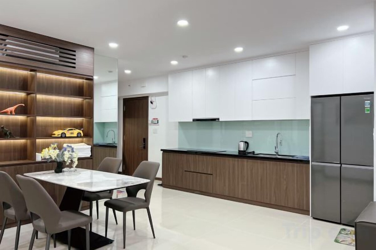 A modern kitchen with a dining area, white cabinets, and a stainless steel refrigerator.