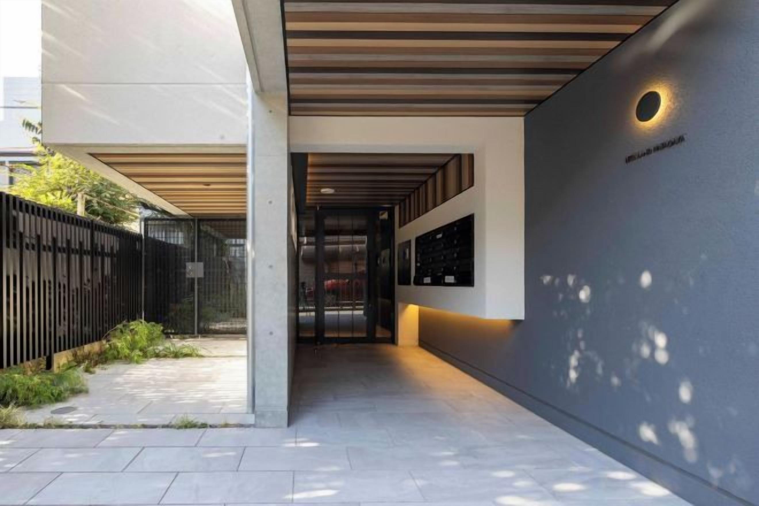 A corridor with a modern design, featuring a concrete floor and a metal fence on one side.