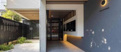 A corridor with a modern design, featuring a concrete floor and a metal fence on one side.