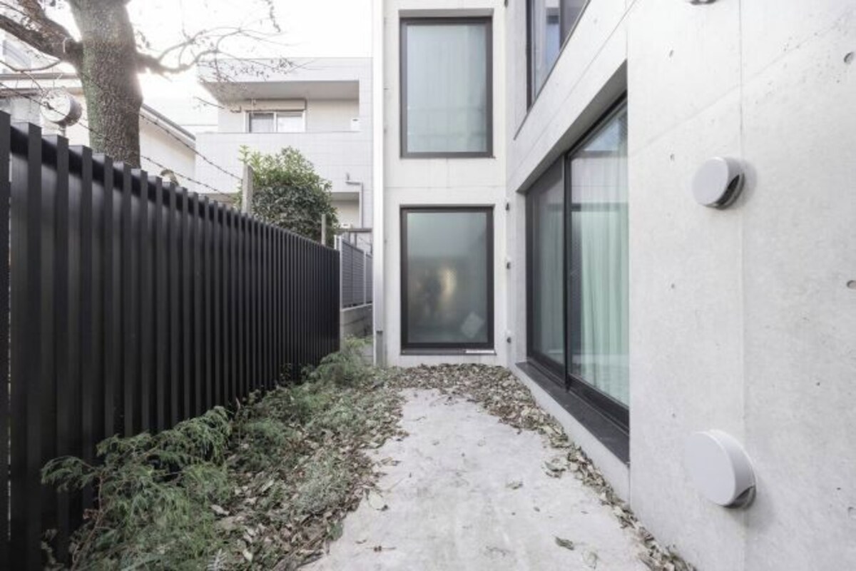 A modern building with a concrete exterior, a black metal fence, and a concrete pathway.