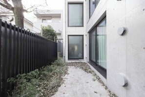 A modern building with a concrete exterior, a black metal fence, and a concrete pathway. - LEGALAND Hatagaya (Tokyo)