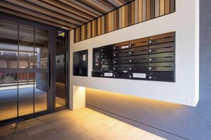A hotel entrance with a glass door, a wall-mounted keycard system, and a tiled floor. - LEGALAND Hatagaya (Tokyo)