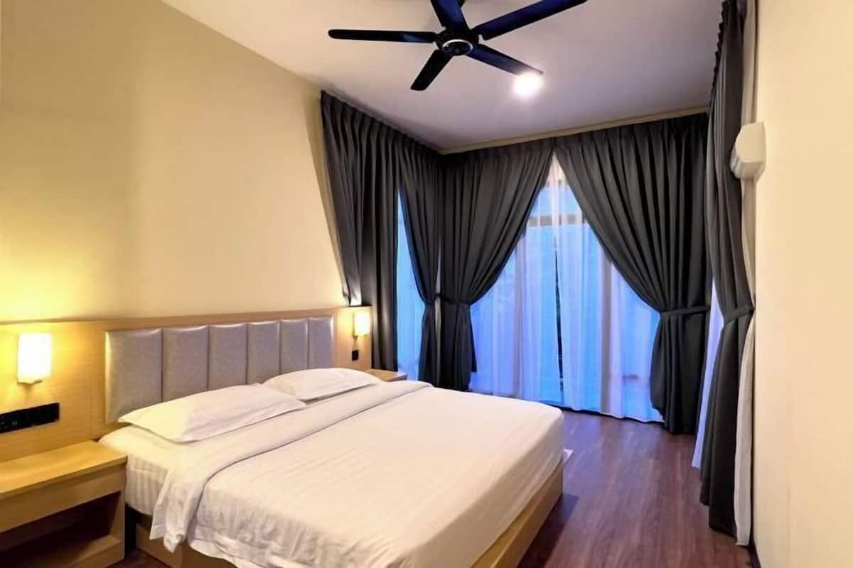 A hotel room with a bed, a ceiling fan, a nightstand, and a window with curtains.