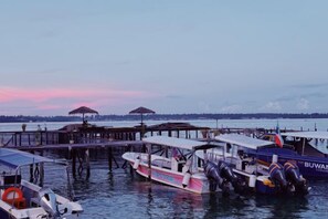 A marina with boats docked at wooden piers, some with umbrellas. - The Buwan Dive Resort (Semporna)