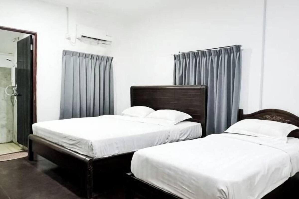 A room with two beds, a shower, and curtains.