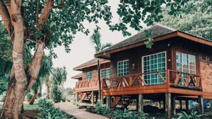 Une cabane en bois dotée d’un balcon, entourée d’une végétation luxuriante et d’arbres.