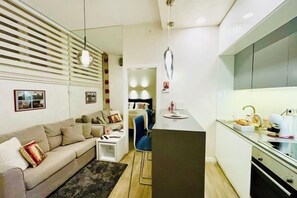 A modern living room with a sofa, a coffee table, and a dining area with a kitchen counter. - LIRRA LUXE (Belgrade)