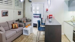 Una sala moderna con sofá, comedor y kitchenette.