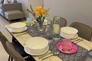 A dining table set with plates, cutlery, and a pink cup, with a vase of flowers and salt shakers on the table. - 7 Pax Genting View Nearby Mont Kiara Desa Park 500Mbps Netflix (Kuala Lumpur)