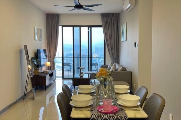 Un coin repas avec une table dressée pour quatre personnes, un ventilateur de plafond et une vue dégagée grâce à de grandes fenêtres.