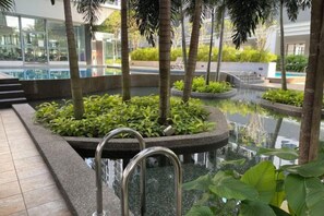 Un espace piscine agrémenté de plusieurs éléments aquatiques, entouré de verdure et de palmiers.