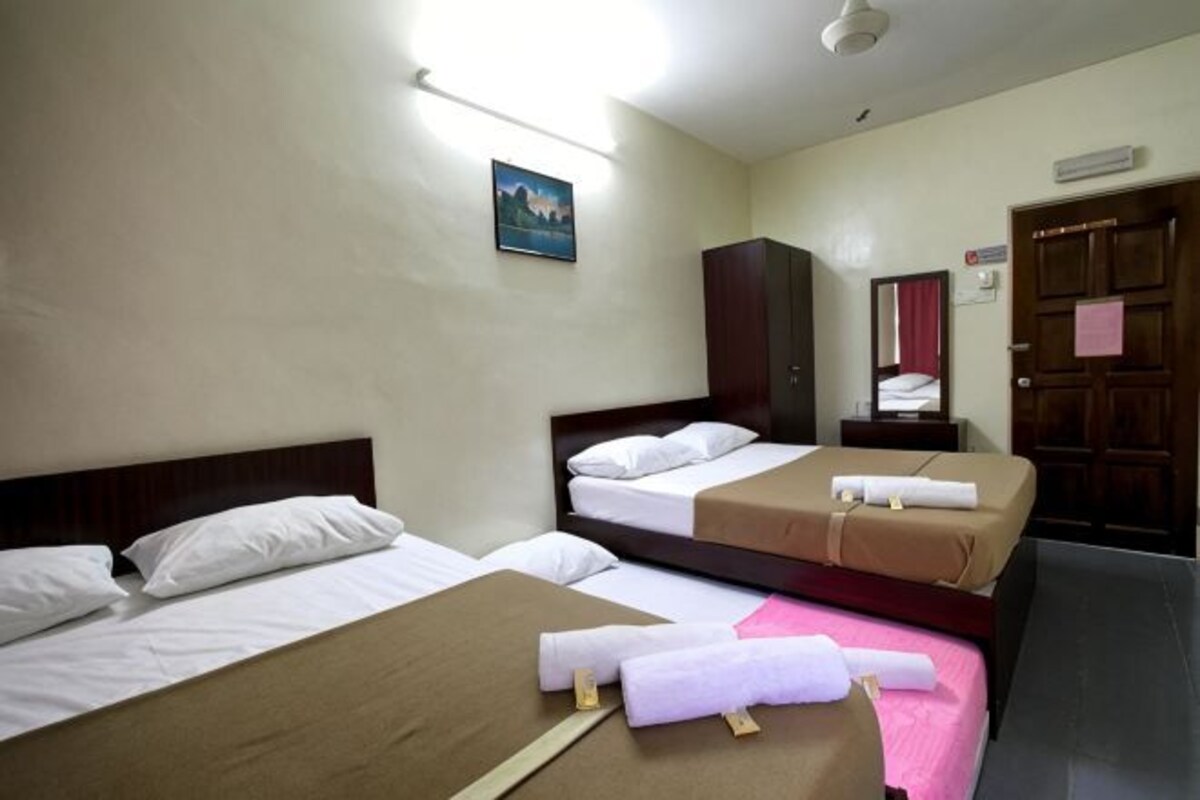 A hotel room with two beds, a wardrobe, a mirror, and a door with a sign.