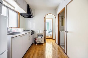 A compact kitchen with white cabinets, a microwave, and a small countertop. - Nishikameari 2 chome (Tokyo)