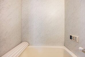 A bathroom with a bathtub, a control panel, and a towel rack. - Nishikameari 2 chome (Tokyo)
