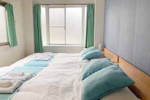 A hotel room with a bed, pillows, and a window. - Nishikameari 2 chome (Tokyo)