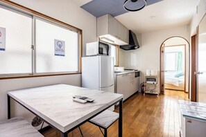A compact hotel room with a kitchenette, a dining area, and a bed. - Nishikameari 2 chome (Tokyo)