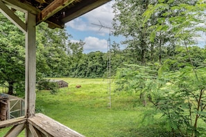 A wooden structure with a metal antenna, surrounded by lush greenery and a distant barn. - Misty Meadows, peaceful farmhouse (Bloomington)