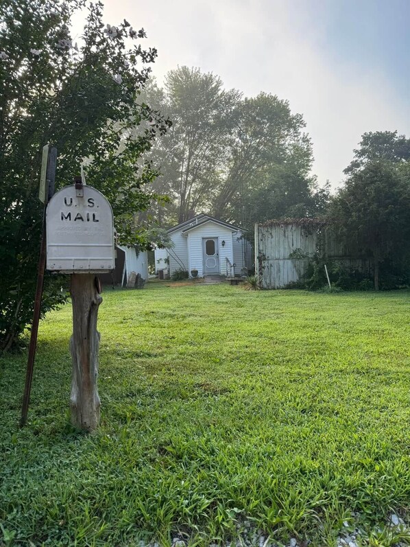 A U.S. Mail mailbox in a grassy yard with a small white building in the background. - Misty Meadows, peaceful farmhouse (Bloomington)
