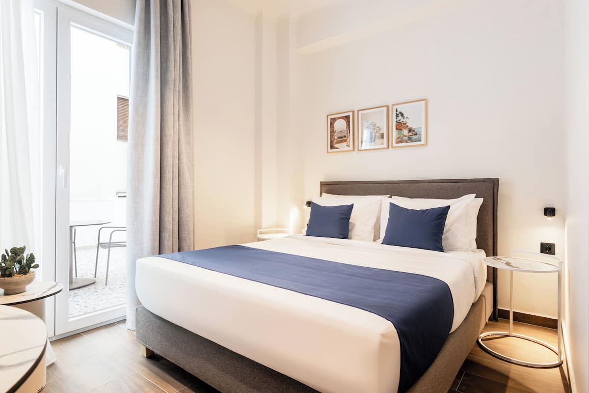 Ein Hotelzimmer mit einem großen Bett, einem Nachttisch, einem kleinen runden Tisch und einer Topfpflanze.