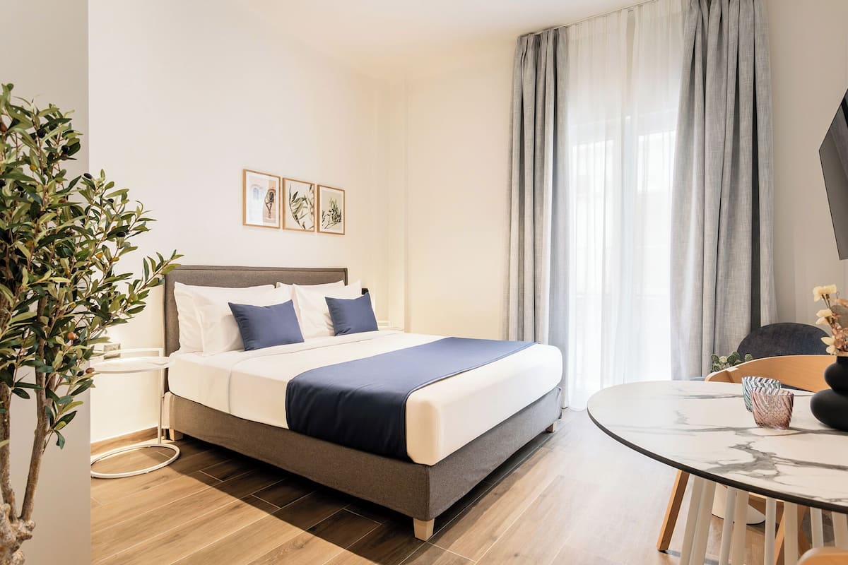 Ein modernes Hotelzimmer mit Bett, Nachttisch und einem runden Esstisch.