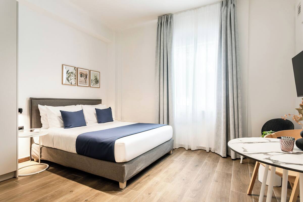 Ein modernes Hotelzimmer mit Bett, Nachttisch und Esstisch.