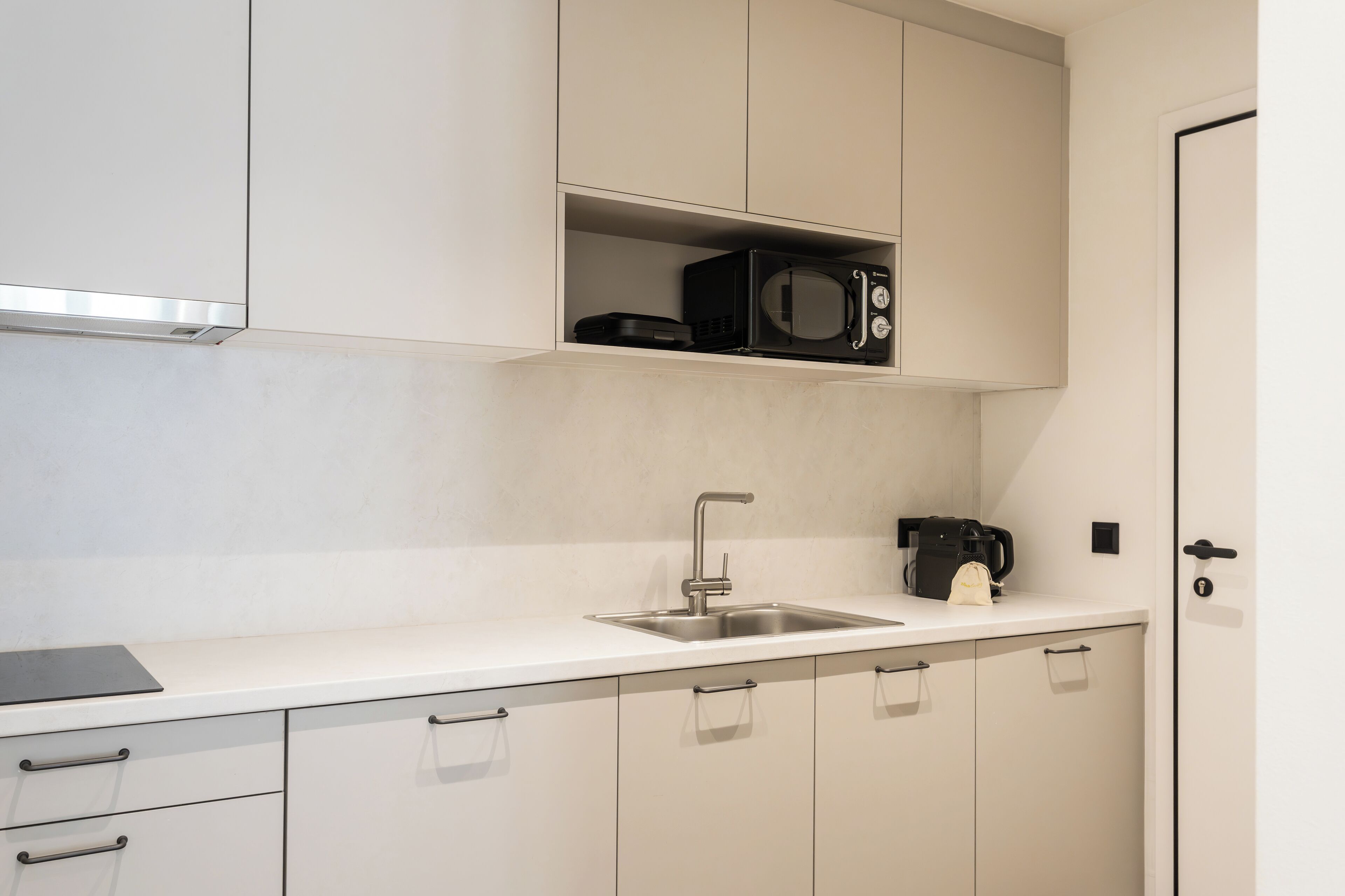 A modern kitchen with a white countertop, stainless steel sink, and cabinets.