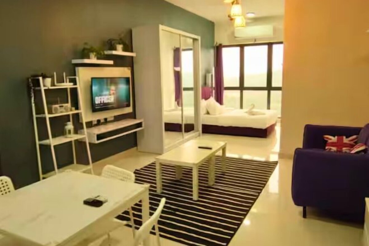 A modern living room with a flat-screen TV, a sofa, a dining table, and a large window offering a view.