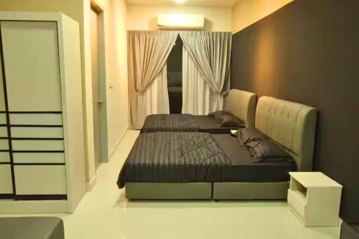 A bedroom with a bed, curtains, a bedside table, and a wardrobe.